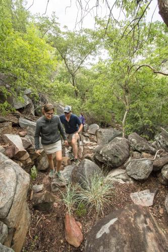 a couple of people walking down a rocky trail at Xaro Lodge in Shakawe