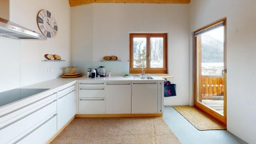 a white kitchen with a sink and a window at Funtanella in Samedan