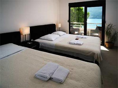 two beds in a bedroom with a view of the ocean at Apartments Twins in Herceg-Novi