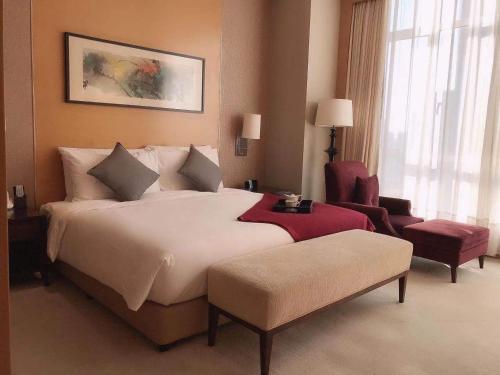 a hotel room with a large bed and a chair at Somerset Grand Central Dalian in Dalian