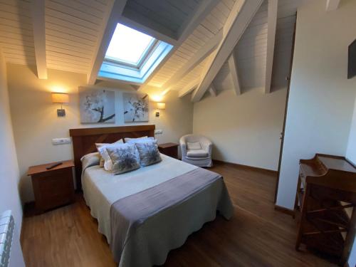 a bedroom with a large bed and a skylight at Pensión Arbidel in Ribadesella