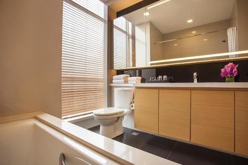 a bathroom with a toilet and a sink and a tub at Somerset Grand Central Dalian in Dalian