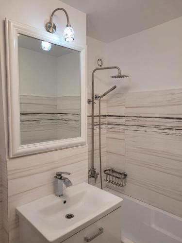 a white bathroom with a sink and a shower at Neversea Apartment in Constanţa