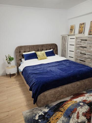 a bedroom with a large bed with a blue blanket at Neversea Apartment in Constanţa