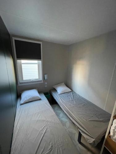 two beds in a small room with a window at Camping LES PEUPLIERS in Hyères