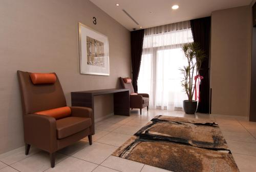 a living room with a chair and a desk at Dormy Inn Nagasaki Shinchichukagai in Nagasaki