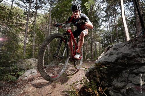 a man riding a bike on a trail in the woods at Hotel Paradiso Conca d'Oro in Nago-Torbole