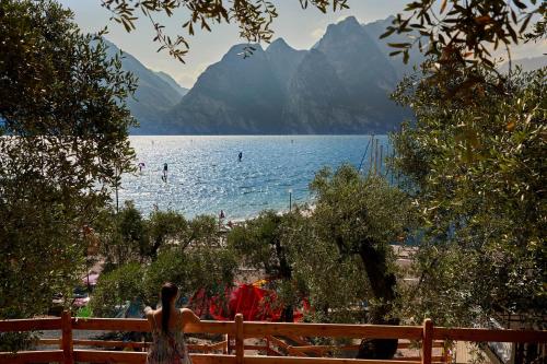 a woman standing on a fence looking at a lake at Hotel Paradiso Conca d'Oro in Nago-Torbole
