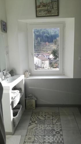 La salle de bains est pourvue d'une fenêtre, d'une baignoire et d'un lavabo. dans l'établissement GÎTE AU TILLEUL pour 8 personnes, à Mariac