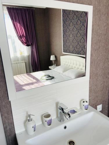 La salle de bains est pourvue d'un lavabo et d'un miroir au-dessus du lit. dans l'établissement Готель Лаванда на Ривьере , Карпатский чан, Фонтанка 1 Одесса, à Fontanka