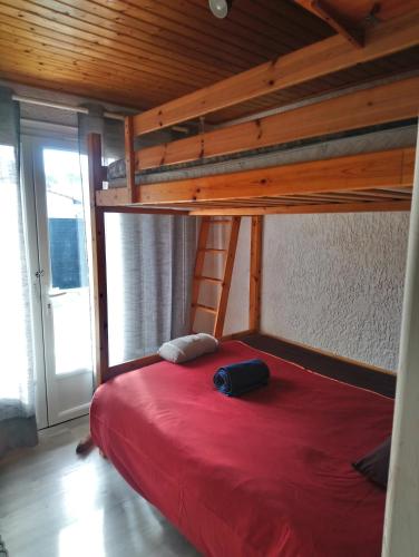 une chambre avec un lit superposé avec un couvre-lit rouge dans l'établissement Bassin d'Arcachon - studio Ares -, à Arès