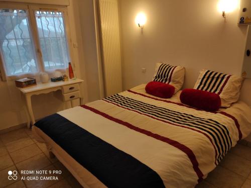 une chambre avec un grand lit avec deux oreillers rouges dans l'établissement Chez Marie, à Alès