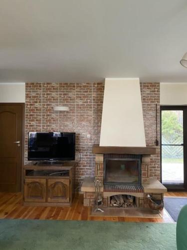 a living room with a fireplace and a television at Dom nad jeziorem Sławskim in Lubiatów