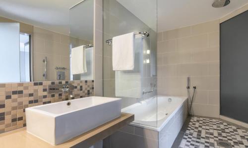 a white bathroom with a tub and a sink at Radisson Blu Gautrain Hotel, Sandton Johannesburg in Johannesburg