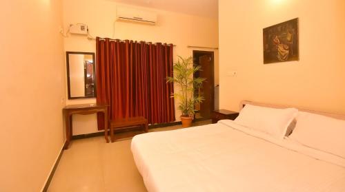 a bedroom with a white bed and a red curtain at villa Freddy in Puducherry