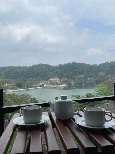 two coffee cups on a wooden table with a view of the water at Lotus Lake Residence in Kandy