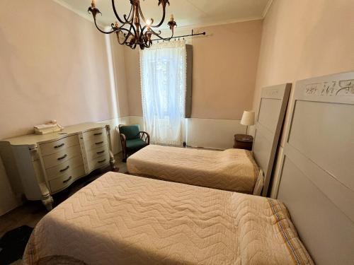 a bedroom with two beds and a dresser and a chandelier at Spacious villa with private pool in Ca' dei Rovati in Castana