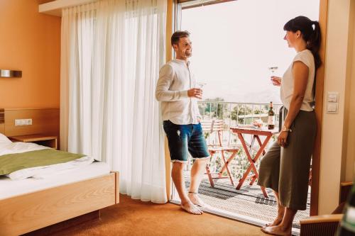 a man and a woman standing in a hotel room with a window at Weingut Kollerhof am Eichberg in Leutschach