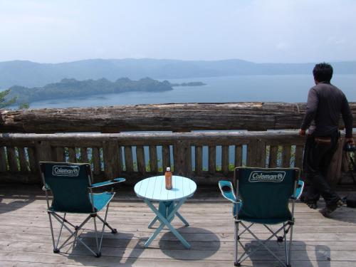 a man walking on a deck with two chairs and a table at Towadako Backpackers in Towada