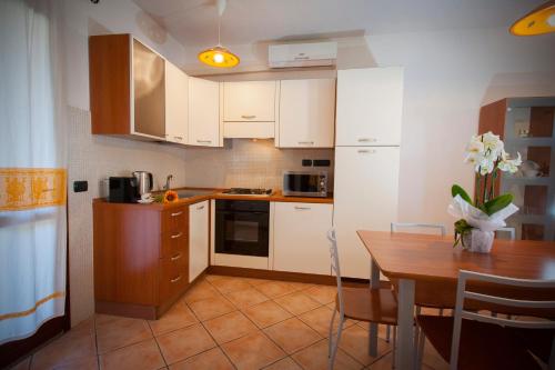 a kitchen with white cabinets and a wooden table at Ville del Mar in San Teodoro