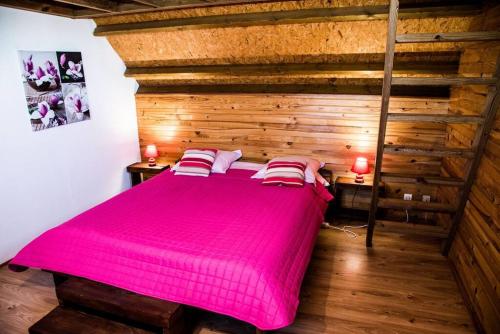 a large pink bed in a room with wooden walls at Chalet des Hauts- Vue piton des neiges in Le Tampon