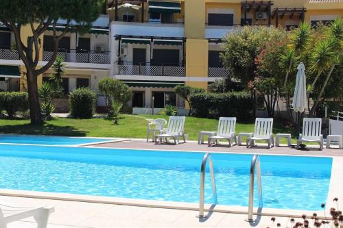 a swimming pool with chairs and a building at Seahorse House, T2 Tavira – Santa Luzia in Tavira