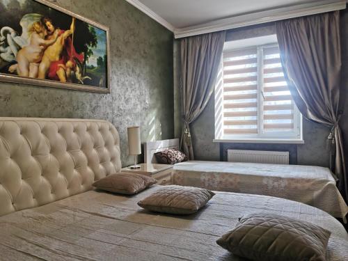 a bedroom with two beds and a painting on the wall at Chernigov City Centre Apartments in Chernihiv