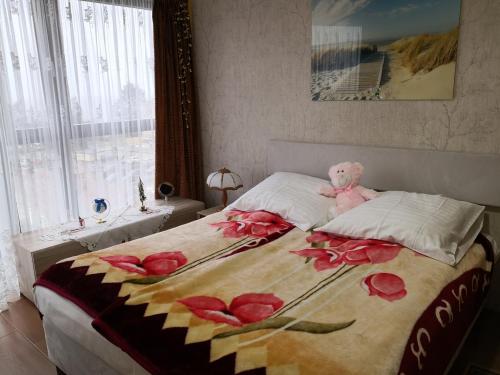 Różowy miś siedzący na łóżku w obiekcie Apartament Sova w mieście Międzyzdroje
