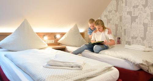 a man and a woman sitting on beds at Familienhotel "Rhön Feeling" in Bernshausen