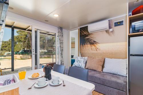 a dining room with a table and a couch at Hemy Casa - Lux Mobile Homes in Rovinj