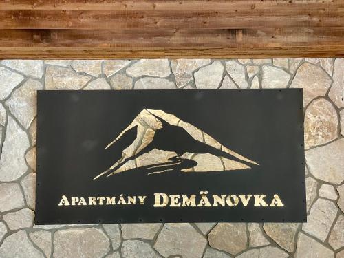 a sign with a bird on a stone wall at Apartmany Demänovka in Demanovska Dolina