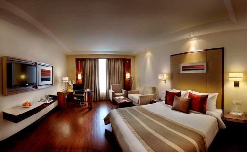 a hotel room with a large bed and a living room at Park Inn Gurgaon in Gurgaon