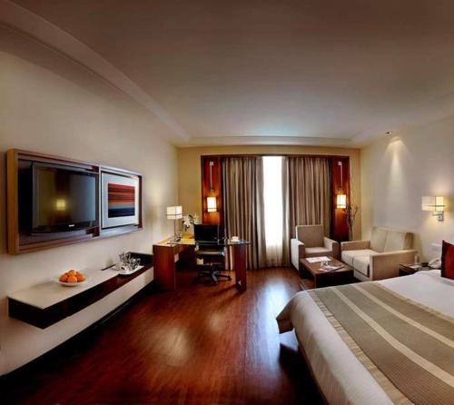 a hotel room with a bed and a living room at Park Inn Gurgaon in Gurgaon