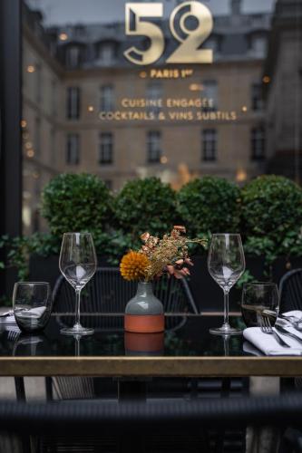 a table with three wine glasses and a vase with flowers at Grand Hôtel Du Palais Royal in Paris