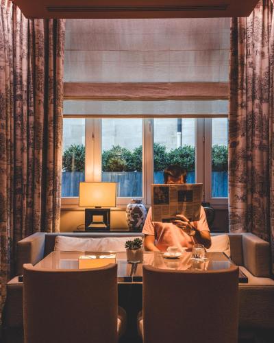 a woman sitting at a table in front of a window at Grand Hôtel Du Palais Royal in Paris
