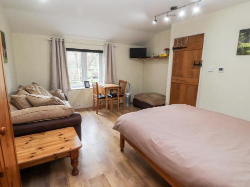 a bedroom with a bed and a table and a chair at Little Pandy Cottage in Mold