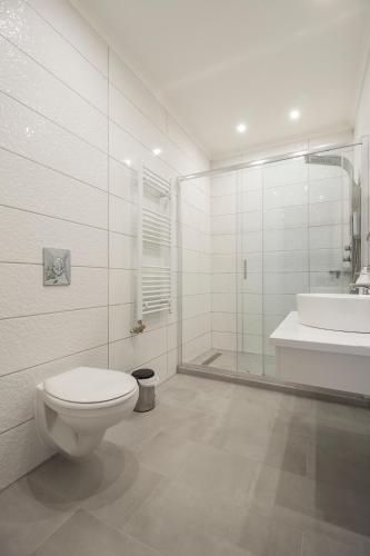 a white bathroom with a toilet and a sink at Ponty-Papa Rendezvényház in Dávod