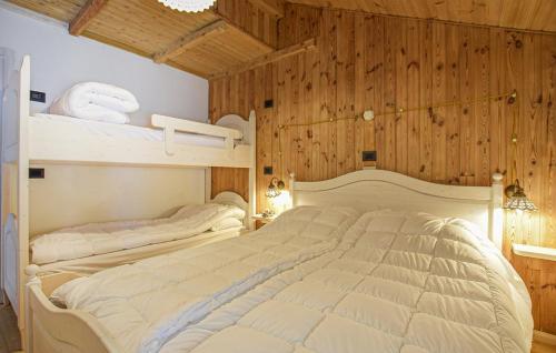 two beds in a bedroom with wooden walls and wooden floors at Chalet Paradisi in Castello Tesino