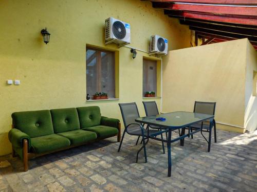 a green couch and a table with chairs and speakers at Korcsetta Vendégház in Dávod