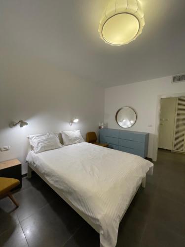 1 dormitorio con 1 cama blanca grande y luz en Beautiful Apartment on The First Line of The Sea en Haifa