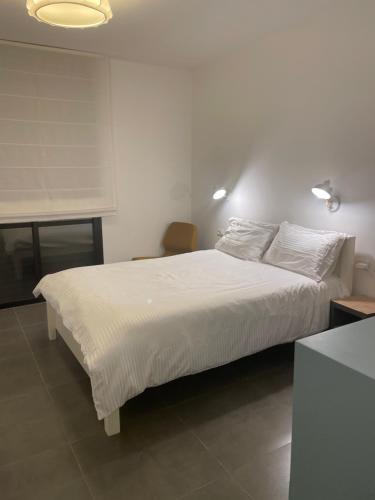 1 dormitorio con 1 cama grande con sábanas y almohadas blancas en Beautiful Apartment on The First Line of The Sea, en Haifa