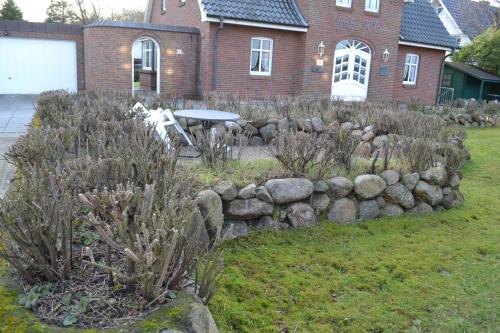 a garden with a stone wall and a table in front of a house at Nordlicht in Wyk auf Föhr