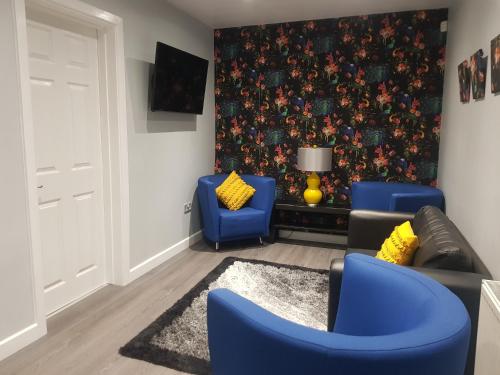 a living room with blue chairs and a wall mural at Saphire Glasgow Apartments in Giffnock