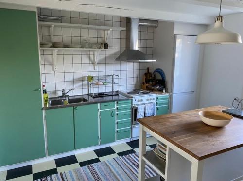 een keuken met groene kasten en een witte koelkast bij Villa Havsro in Farhult