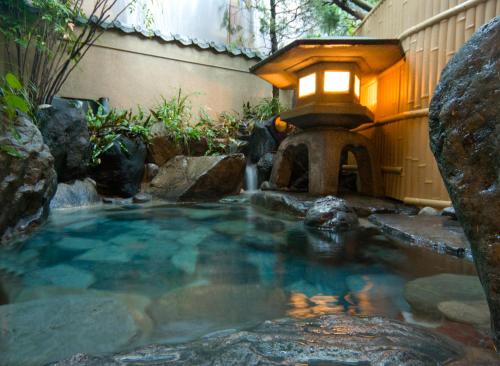 a small pool of water with a lantern and a fountain at Izumi-so in Gero