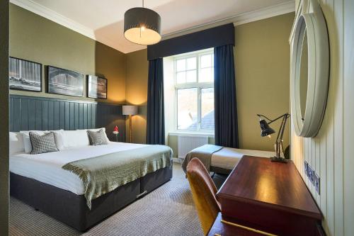 a bedroom with a bed and a desk and a window at Peebles Hydro in Peebles