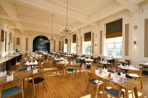 a restaurant with tables and chairs in a room at Peebles Hydro in Peebles