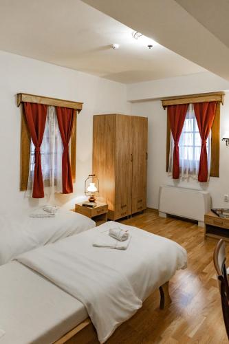 two beds in a room with red curtains at Guest Mansion, Гостински Палат in Rostuša