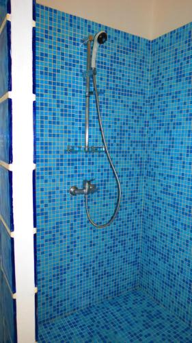 y baño con ducha de azulejos azules. en Kasa MANSA en Kafountine