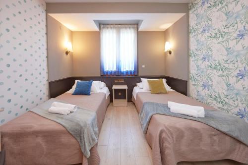 a room with three beds and a window at Hotel Sanchez in Aínsa